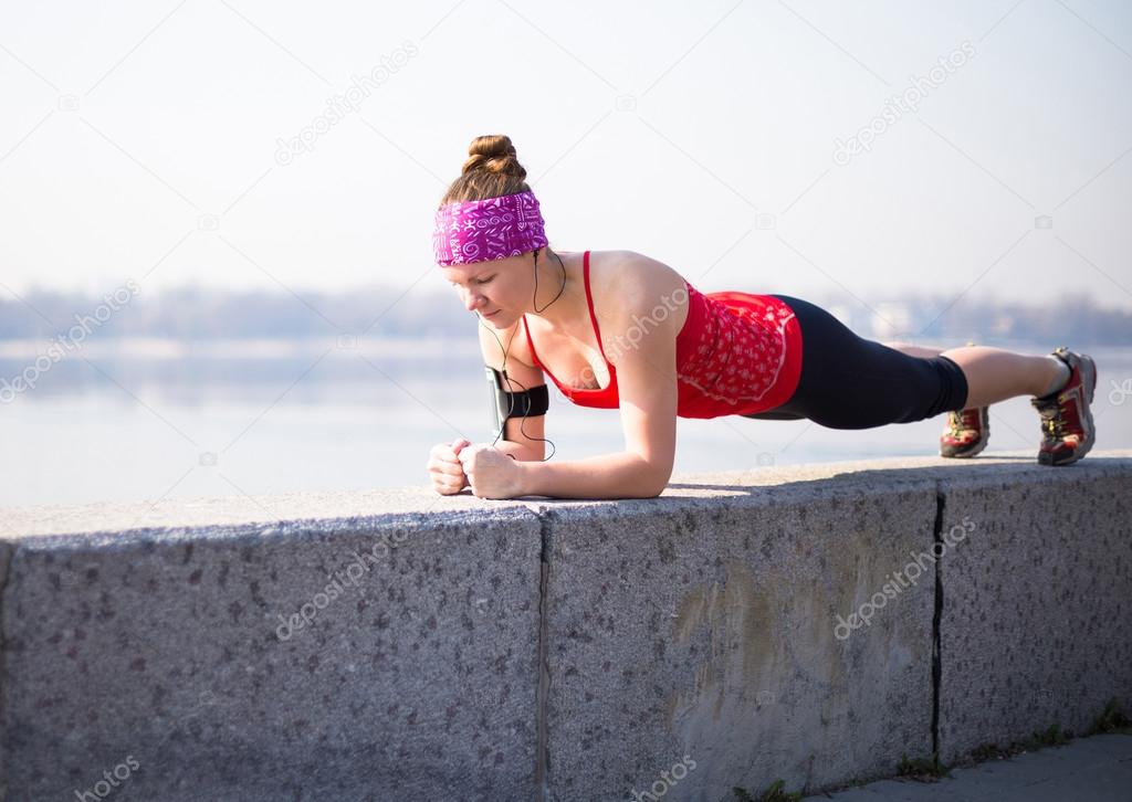 Sport woman doing plank during training outside in city quay early morning