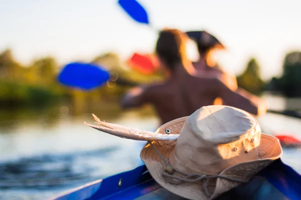 Hat lying on canoe. Young people are kayaking in beautiful nature — Stock Photo, Image