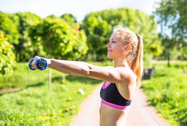Şehir Park dumbbells ile yaz gününde eğitim genç kadın