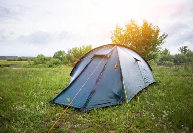 Ormandaki çadır kamp ayakta. Yeşil grassat güneşli sabah ışıkları