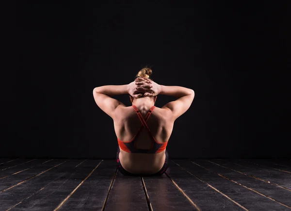Молодая и подтянутая спортивная модель занимается йогой в темной студии — стоковое фото