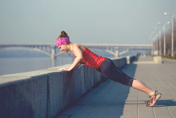 Sport woman doing push-ups outside on city quay in the morning — Stock Photo, Image
