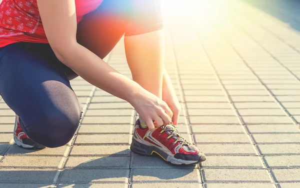 Mujer deportiva atando zapatillas durante el entrenamiento por la mañana — Foto de Stock