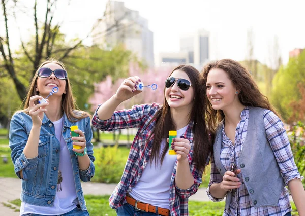Adolescentes soufflant des bulles de savon. Les jeunes adolescents heureux s'amusent dans le parc d'été . — Photo