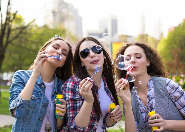 Adolescentes a soprar bolhas de sabão. Jovens adolescentes felizes se divertindo no parque de verão . — Fotografia de Stock