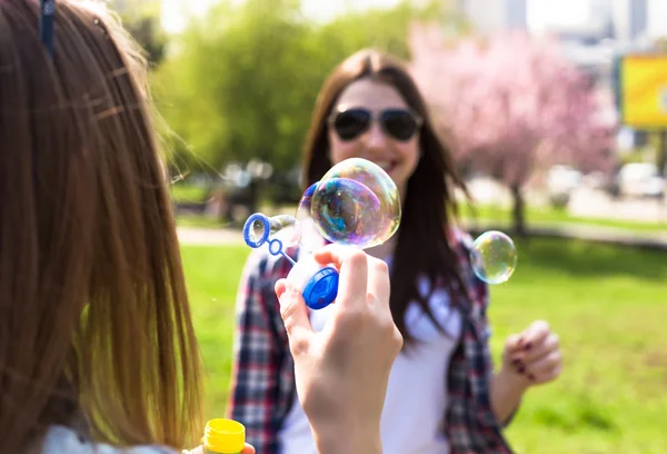 Chicas adolescentes soplando burbujas de jabón. Jóvenes adolescentes felices divirtiéndose en el parque de verano . —  Fotos de Stock