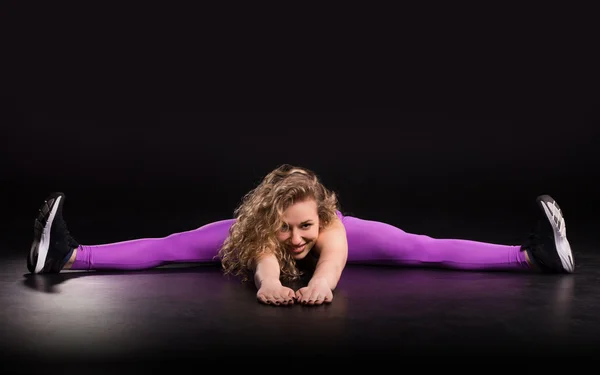 Fitness woman training in dark studio. Young girl stretching — Stock Photo, Image