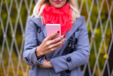 Güzel sonbahar park telefonunu kullanan genç kadın.