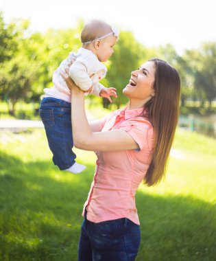 Youmg mutlu bir kadın onun şirin bebek yaz güneşli Park açık ile oynarken. Mothercare resim