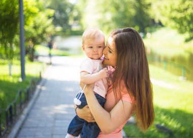 Youmg mutlu bir kadın onun şirin bebek yaz güneşli Park açık ile oynarken. Mothercare resim