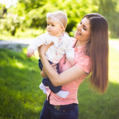 Youmg mutlu bir kadın onun şirin bebek yaz güneşli Park açık ile oynarken. Mothercare resim