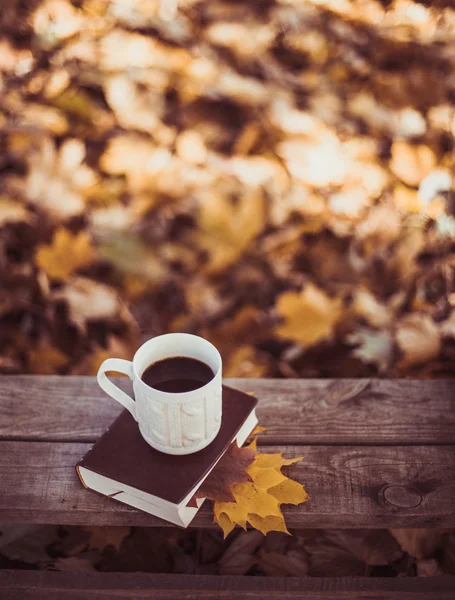 Hete koffie en rode boek met najaar bladeren op hout achtergrond - seizoensgebonden ontspannen concept — Stockfoto