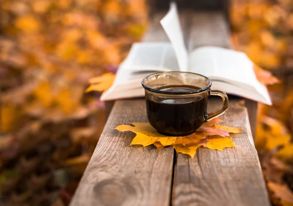 Hete koffie en rode boek met najaar bladeren op hout achtergrond — Stockfoto