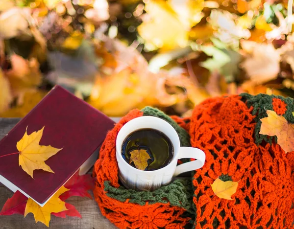 Ζεστό καφέ και κόκκινο βιβλίο με το φθινόπωρο τα φύλλα σε φόντο ξύλου — Φωτογραφία Αρχείου