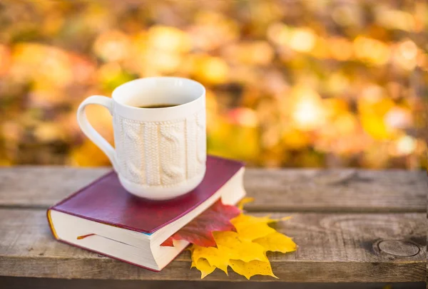 Café quente e livro vermelho com folhas de outono no fundo de madeira — Fotografia de Stock