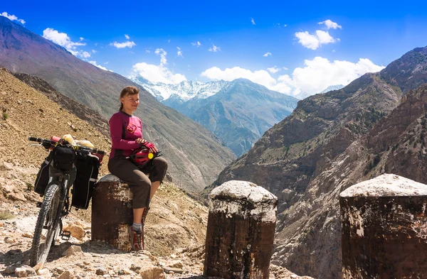 Jovem ciclista mulher sentado na estrada em Himalaia paisagem da montanha. Jammu e Caxemira, Norte da Índia — Fotografia de Stock
