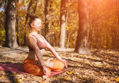 Genç kadın sabah sonbahar Park yoga yaparken