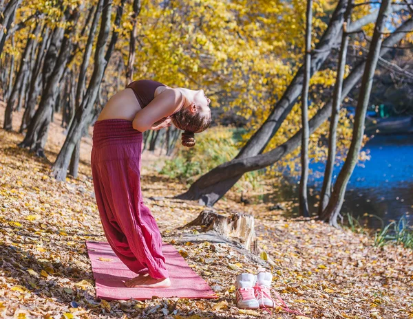Jovem fazendo ioga no parque de outono da manhã — Fotografia de Stock
