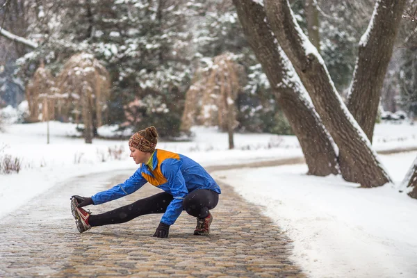 Молодая спортсменка бегает трусцой во время зимних тренировок на улице зимой — стоковое фото