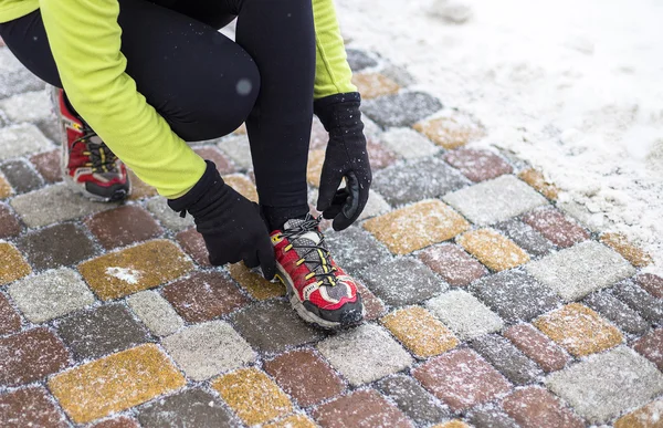 Young sport woman model tying running shoes during winter training outside — Stock Photo, Image