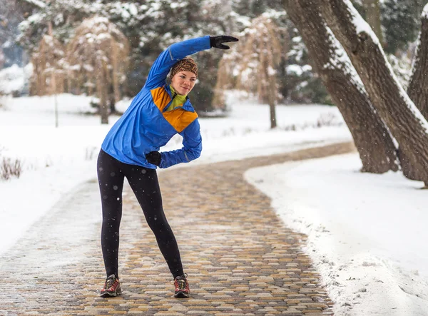 Молодая спортсменка бегает трусцой во время зимних тренировок на улице зимой — стоковое фото
