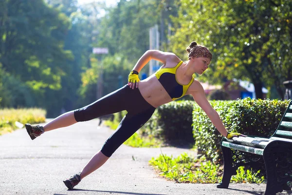 Спортивная женщина делает доску во время тренировок на открытом воздухе — стоковое фото