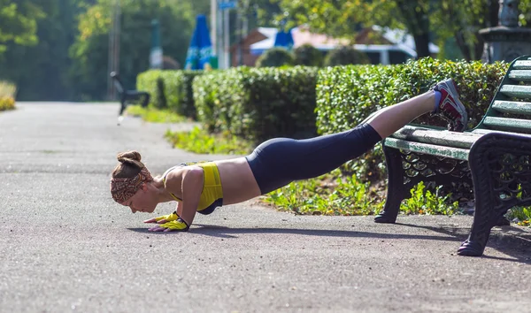 Спортивная женщина делает отжимания во время тренировок на открытом воздухе — стоковое фото