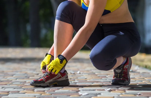 Mujer deportiva atando zapatillas durante el entrenamiento de entrenamiento cruzado al aire libre —  Fotos de Stock