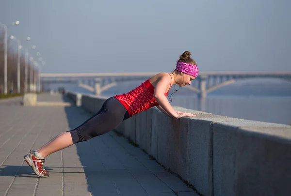 Mujer deportiva entrenando fuera en muelle de la ciudad por la mañana —  Fotos de Stock