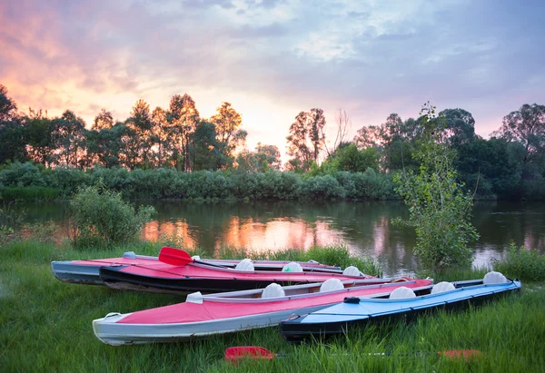 Kayaks rojos y azules cerca de un río en hermosa naturaleza al atardecer —  Fotos de Stock