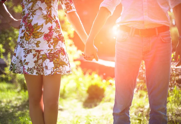 Young couple in love holding hands in the sunset in summer evening