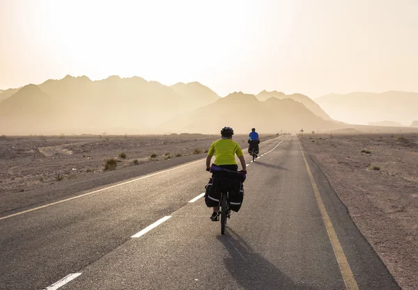 Bicyclists are riding on the road in Israel desert — Stock Photo, Image