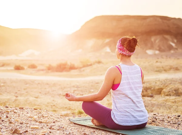 Mujer joven haciendo yoga en el desierto al amanecer —  Fotos de Stock