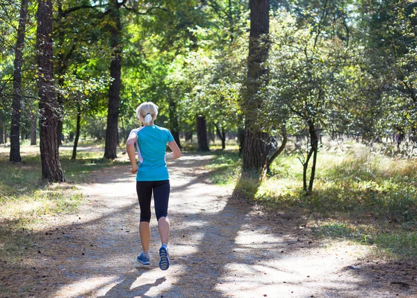Képzés, erdei úton, gyönyörű természeti környezetben futó nő. — Stock Fotó