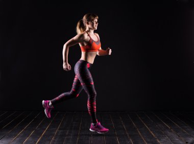 Güzel genç ve formda fitness spor model karanlık Studio'da poz