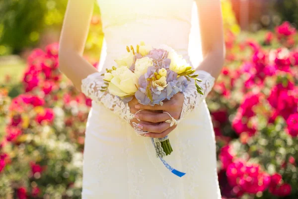 Glad brud med bröllop bouquete poserar på solig dag — Stockfoto