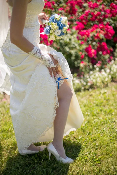 Gelukkige bruid met bruiloft bouquete die zich voordeed op zonnige dag — Stockfoto