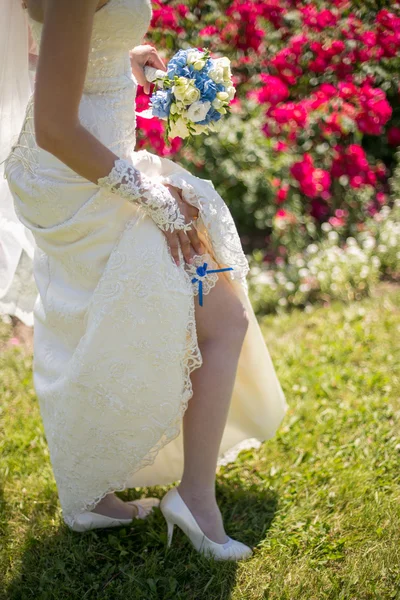 Glückliche Braut mit Brautstrauß posiert an sonnigem Tag — Stockfoto