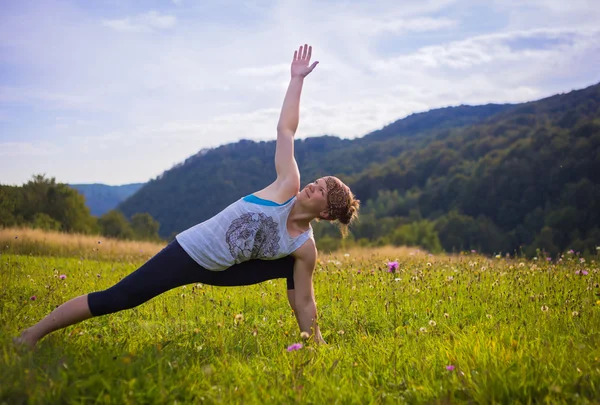 Jovem fazendo ioga nas montanhas ao pôr do sol — Fotografia de Stock
