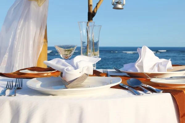 蓝色的大海和沙滩桌享受浪漫晚餐 图库照片