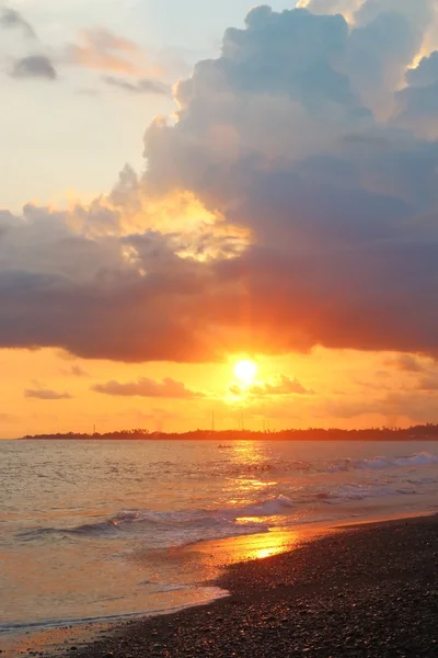 Zonsondergang op het strand met zwart zand Stockfoto