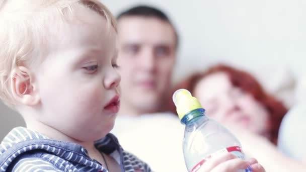 Un petit garçon boit de l'eau d'une bouteille — Video