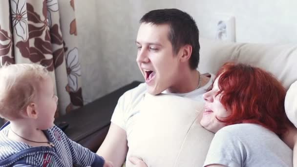 Niño feliz teniendo la atención de sus padres besándolo — Vídeos de Stock