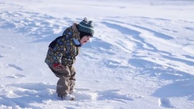 Karda oynayan bir kış şapkalı küçük çocuk