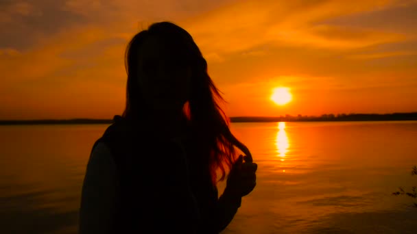 Jong meisje silhouet op het strand tijdens zonsondergang, super slow motion — Stockvideo