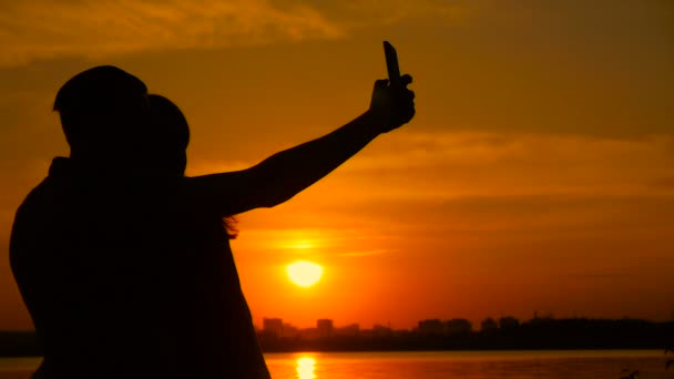 Pasangan muda mengambil foto selfie di pantai selama matahari terbenam, gerakan super lambat — Stok Video