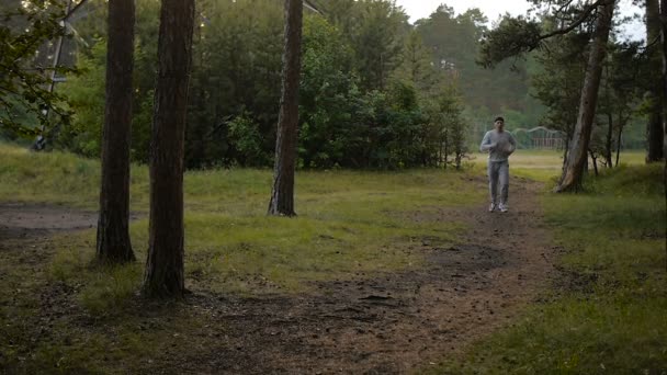 Young sports man in the baseball cap runs through the woods — Stock Video