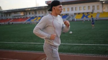 Stadyumda bir yarış pisti üzerinde çalışan genç spor adamı