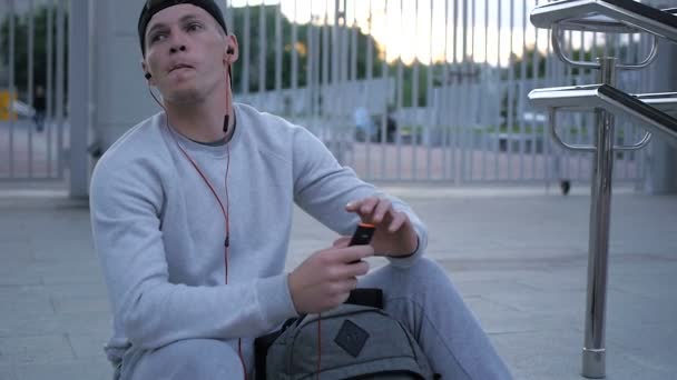 Ralenti du jeune homme porte des écouteurs sur les escaliers du stade — Video