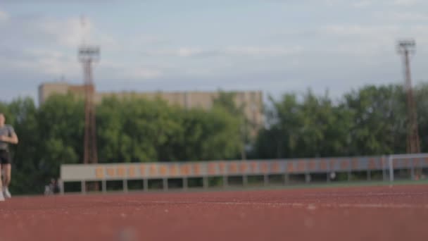 年轻的体育人在跑道上在体育场内运行 — 图库视频影像